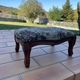 Antique wooden footstool with hand-carved details and floral upholstery –