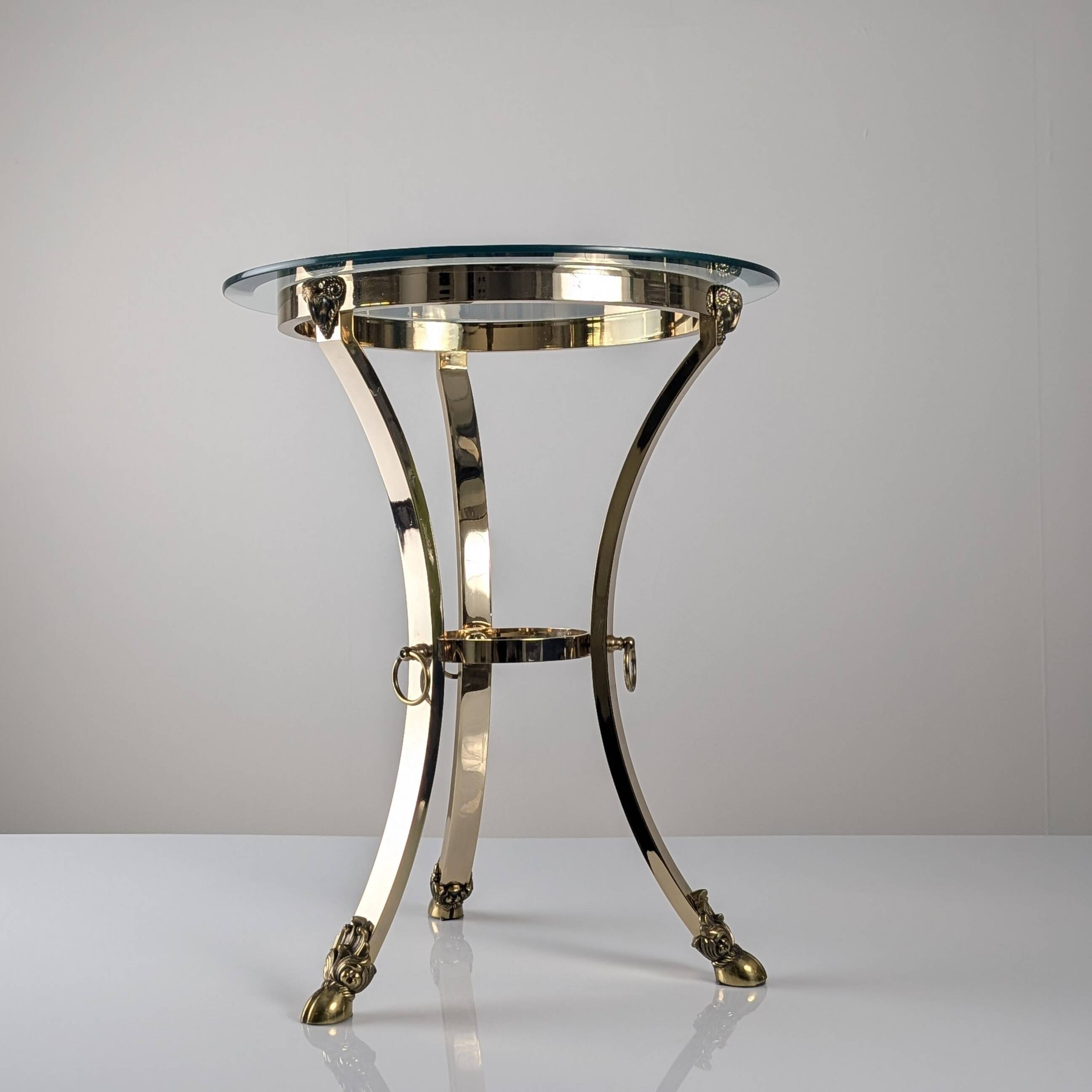 Neoclassical side table in brass and bevelled glass with ram's heads, 1970s.
