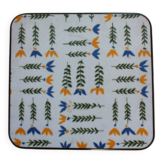 Vintage laminated wooden trivet with yellow, green, and blue flowers