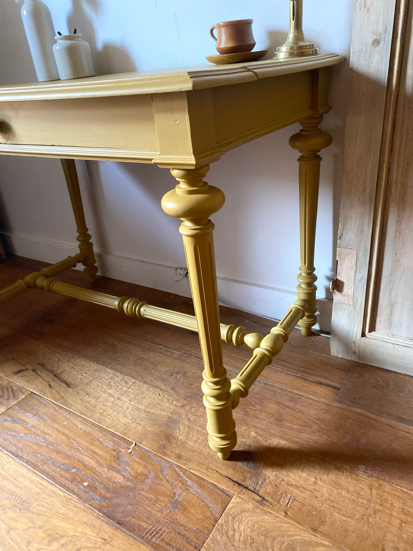 Desk table from the late 19th century, painted mustard, with turned stretcher.