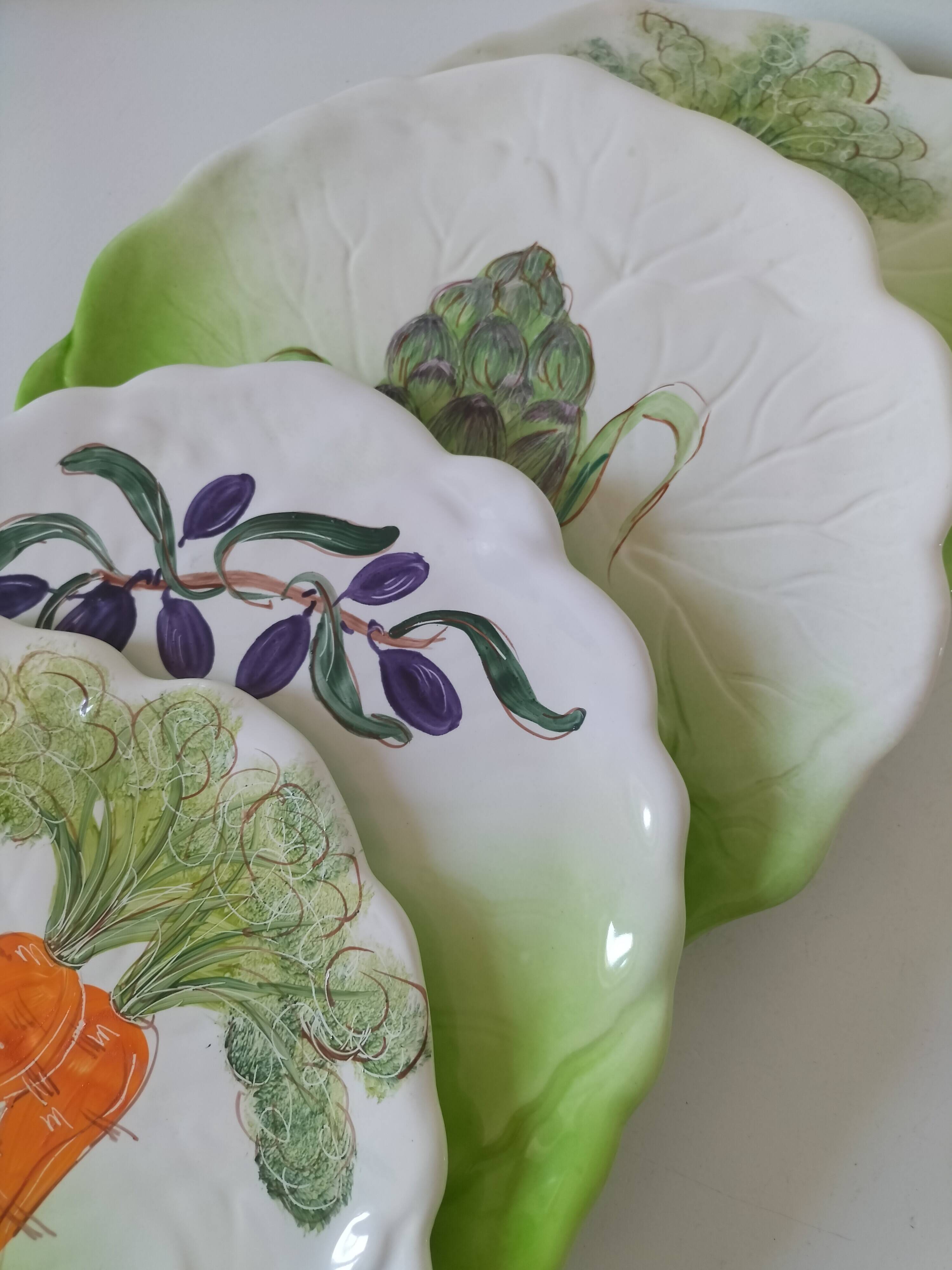 4 hand-decorated earthenware plates with vegetable and green leaf designs.