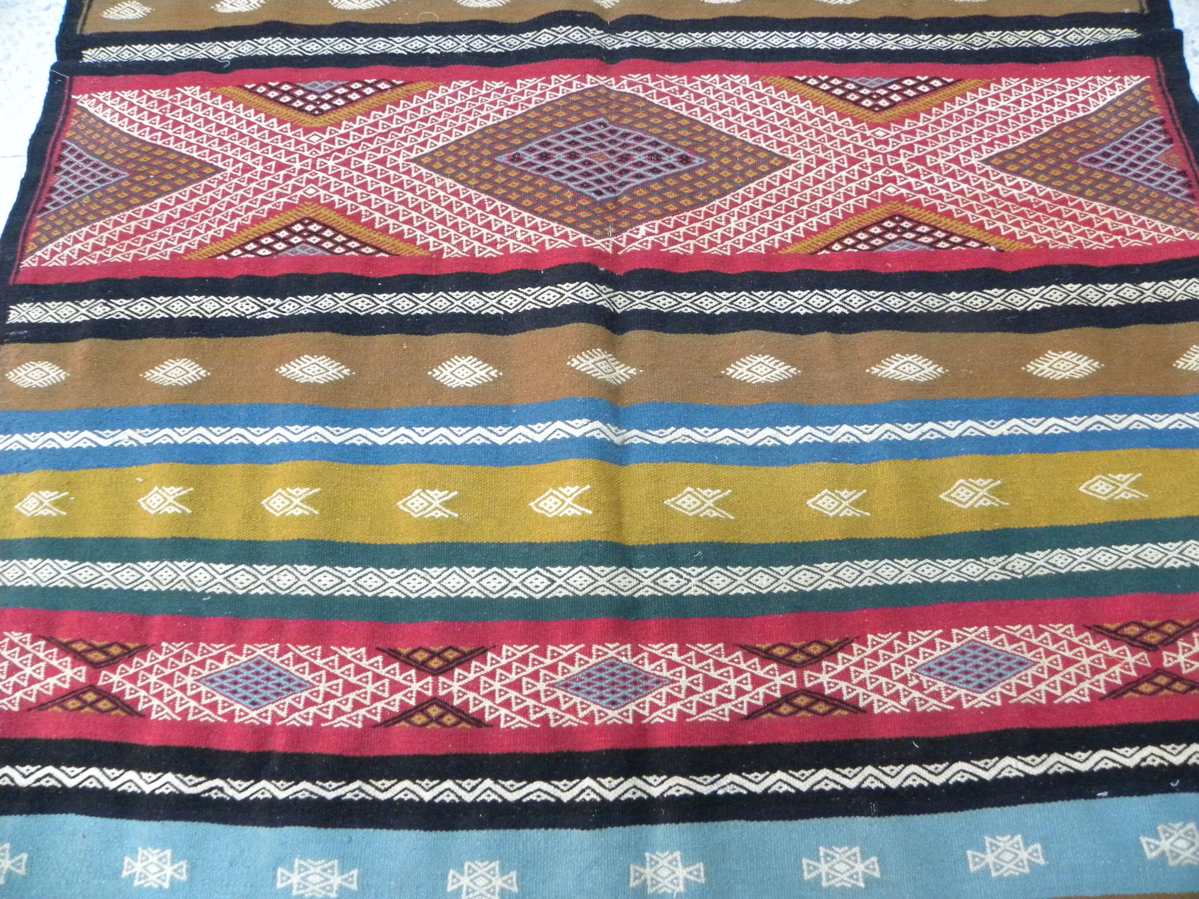 Traditional Berber tribal kilim rug with multicoloured geometric patterns.