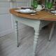 Walnut table with raised flaps, base on verdigris casters.