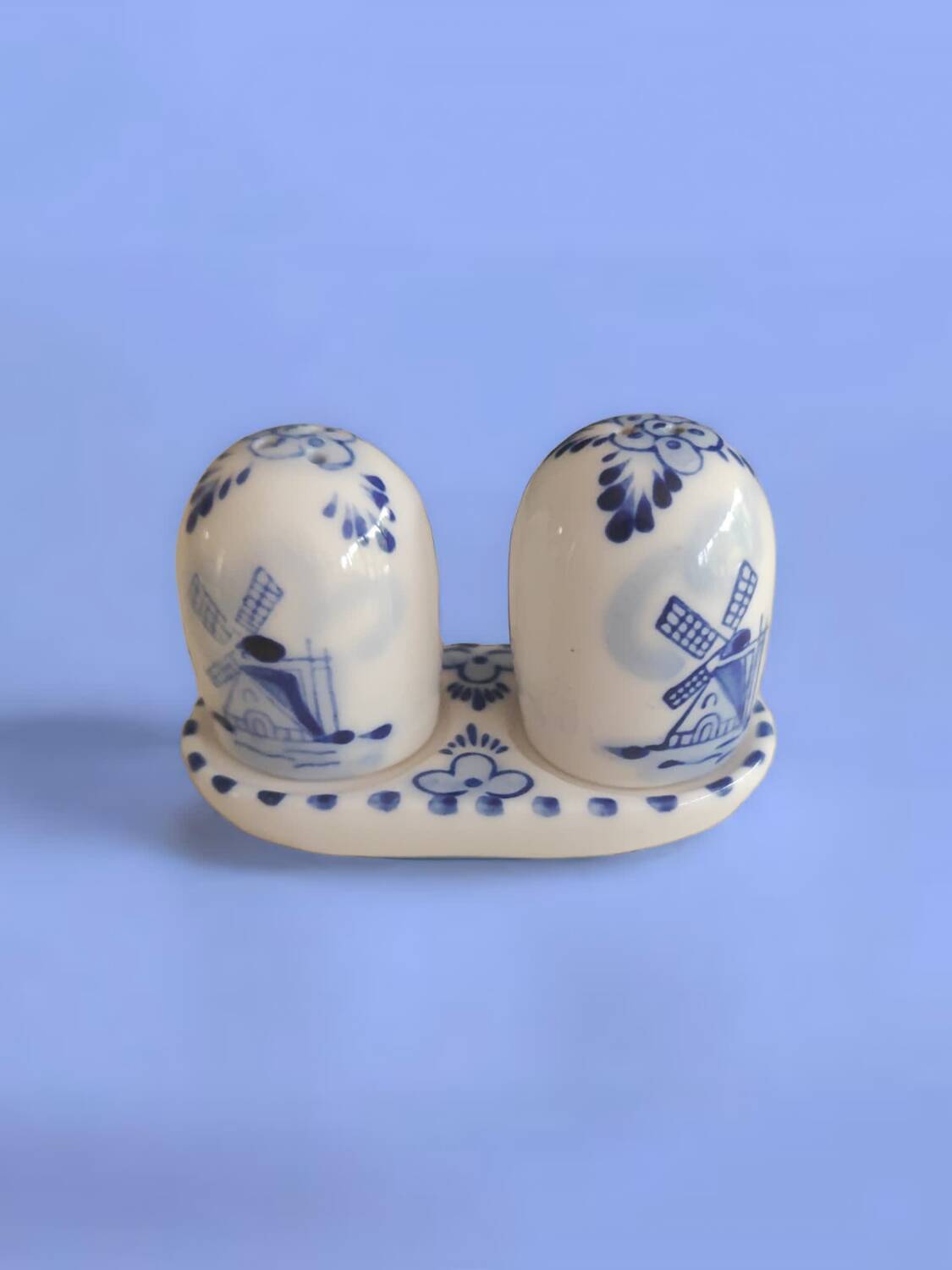 Mini salt and pepper shakers in ceramic with illustrations of Dutch windmills and blue flowers.