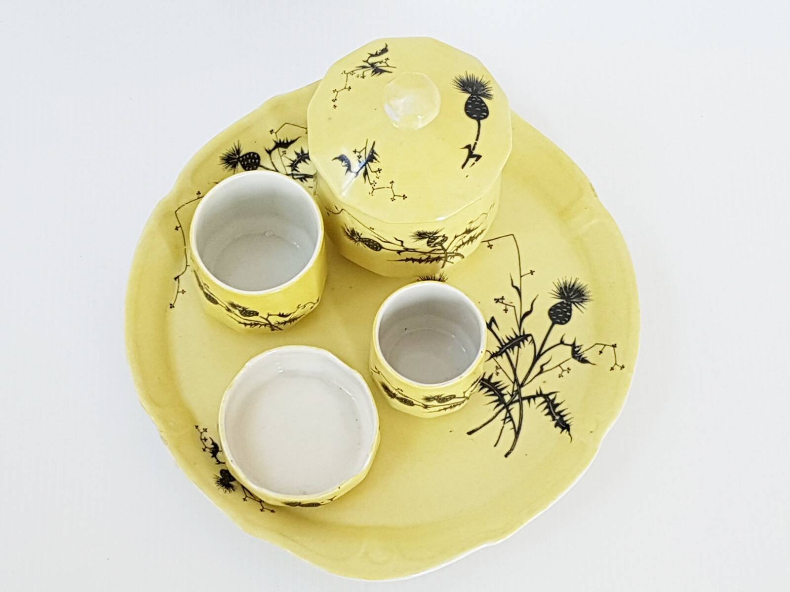 A yellow Art Deco ceramic tobacco service decorated with thistles from the 1920s to 1930s.