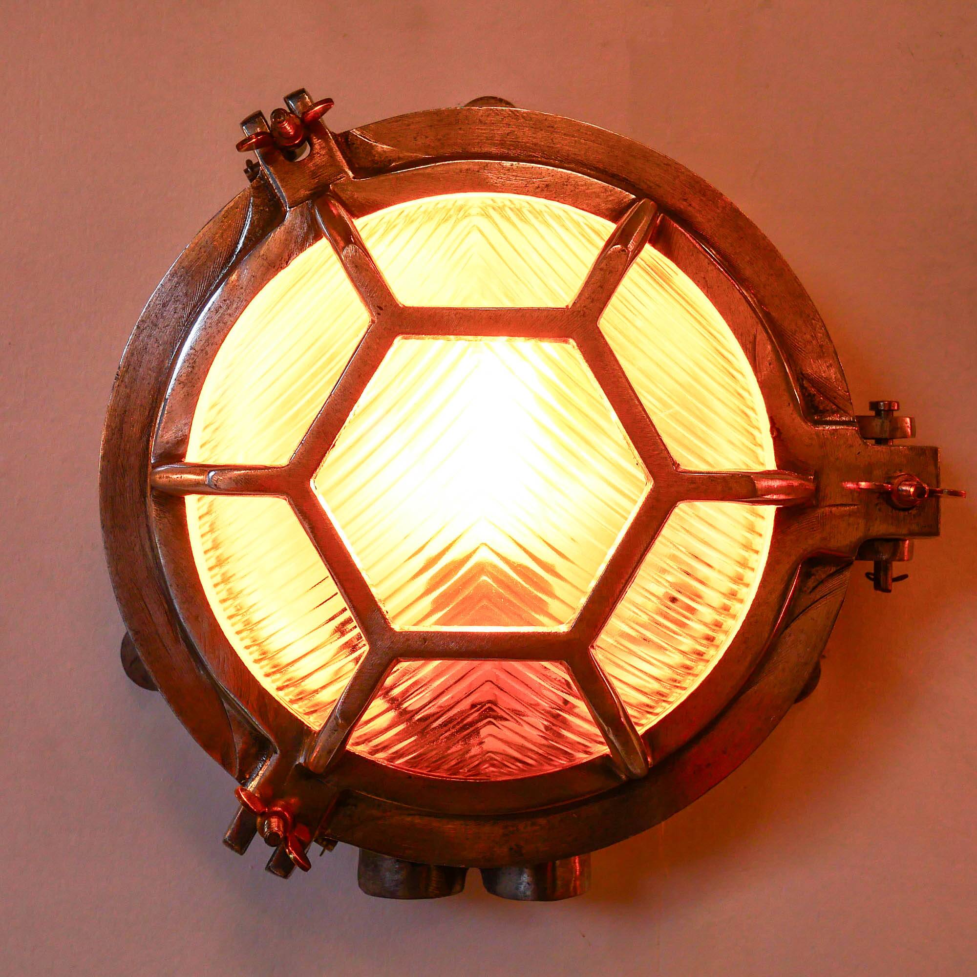 Old cast aluminum wall light with hexagonal grid and wide streaked glass.