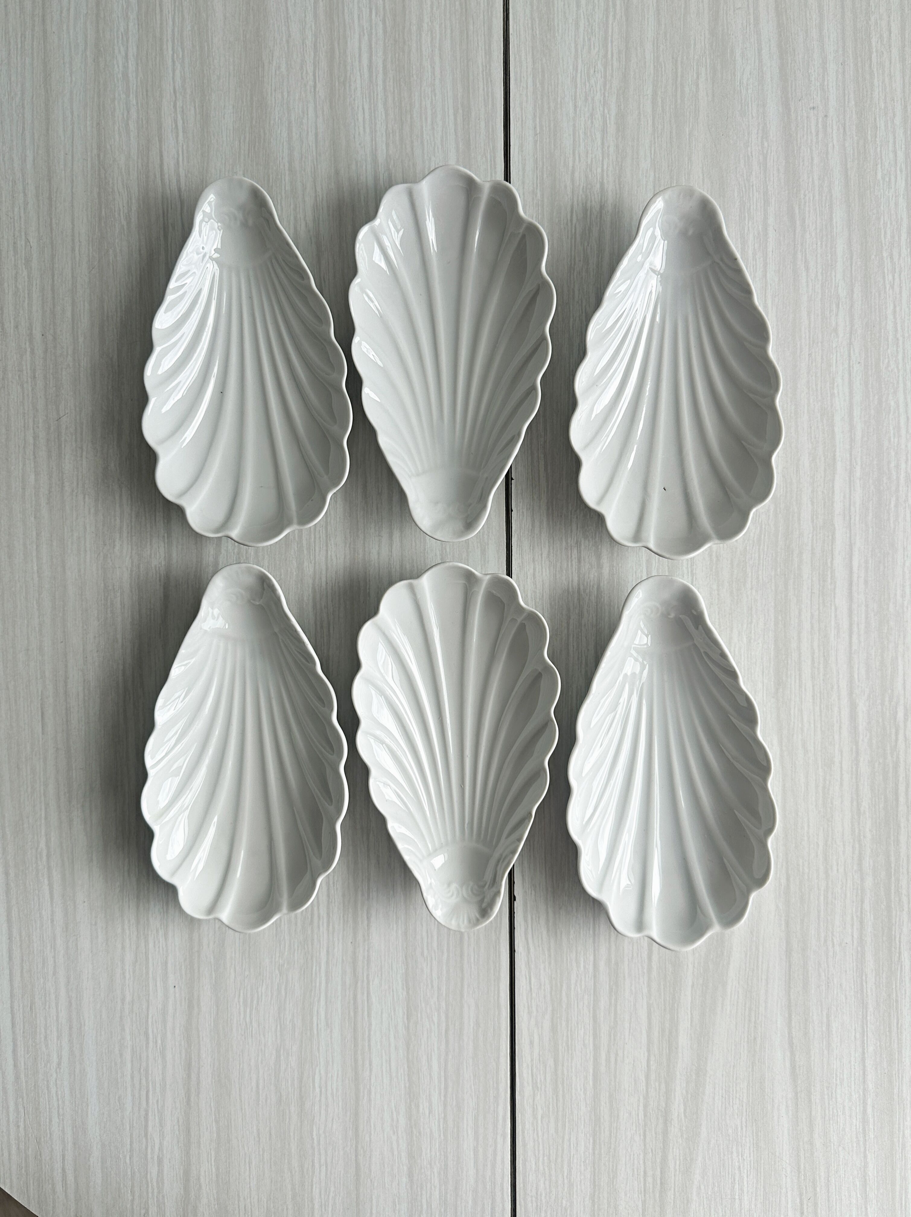 Set of white porcelain ramekins, ribbed shell shape.
