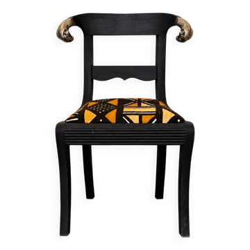 Chaise ancienne en bois noir patiné, tissu africain et têtes de bélier
