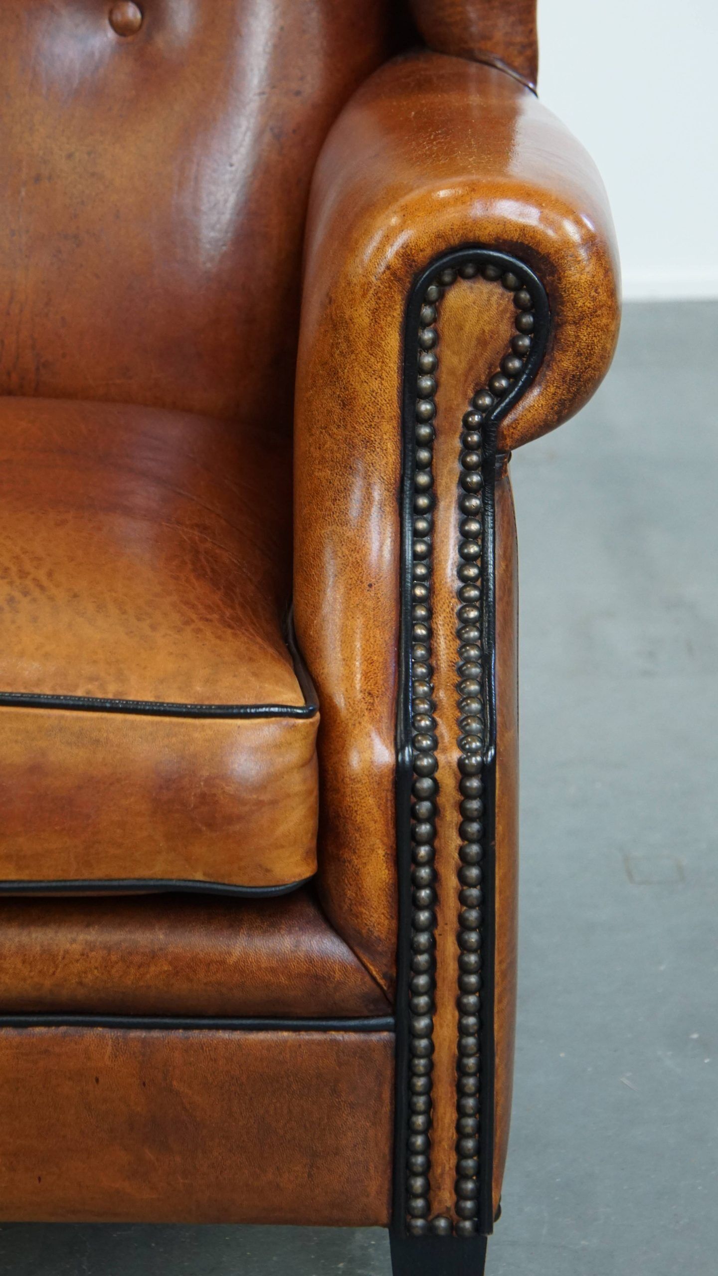 Sheepskin wingback armchair with stitching and black piping