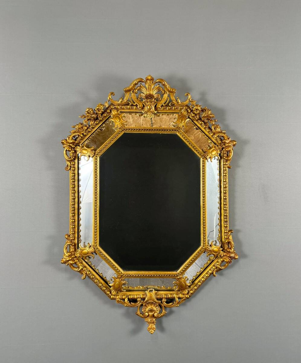 Antique octagonal mirror in richly carved gilded wood, Louis XV style.