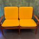 Vintage Scandinavian two-seater bench with mustard yellow cushions.