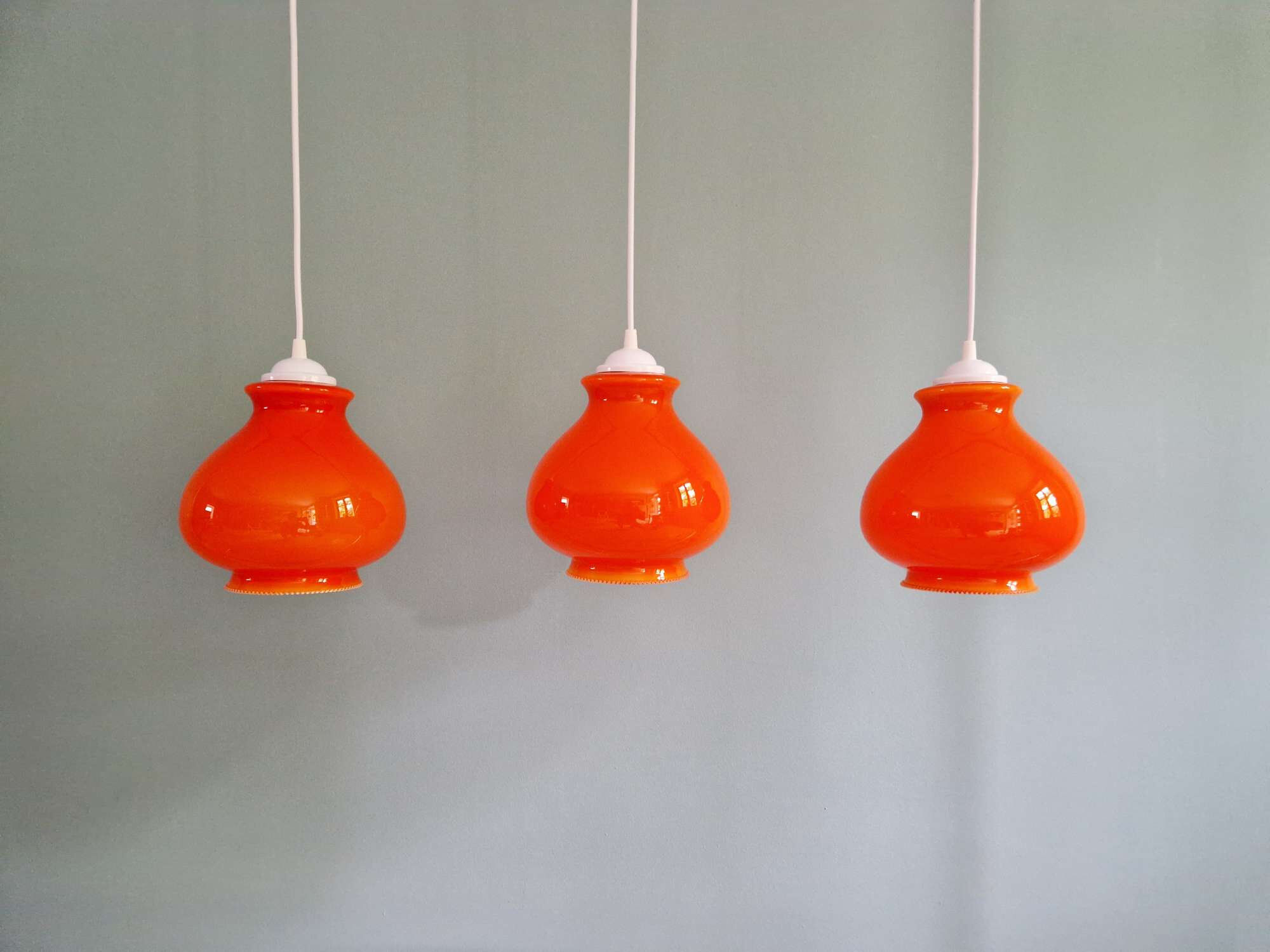 Trio of vintage orange opaline pendant lights, 1960-70