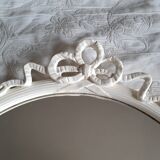 Round mirror in carved wood with at the top a ribbon forming a knot in cream color