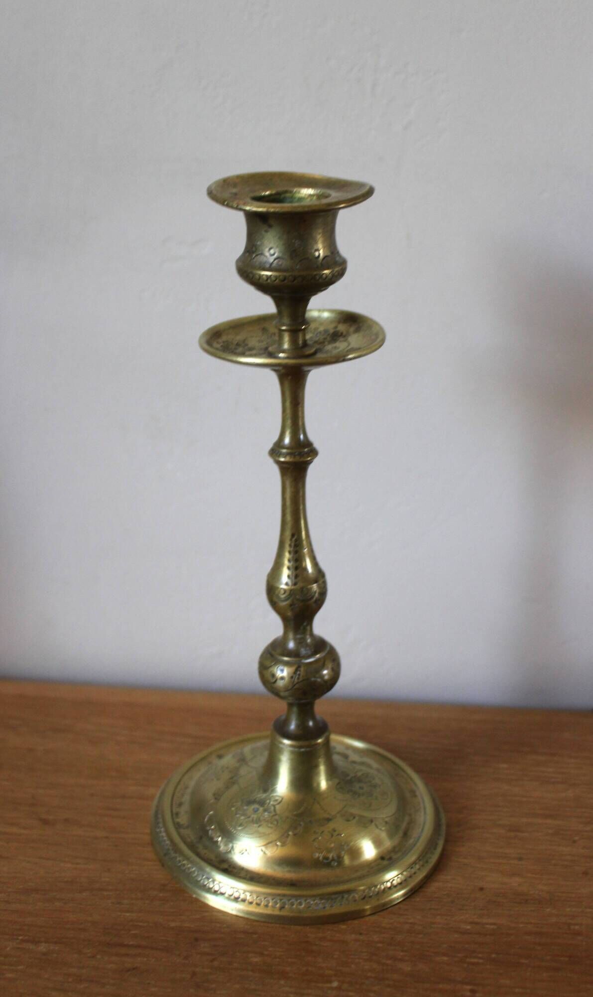 Brass candle holder with flowers and round shape.