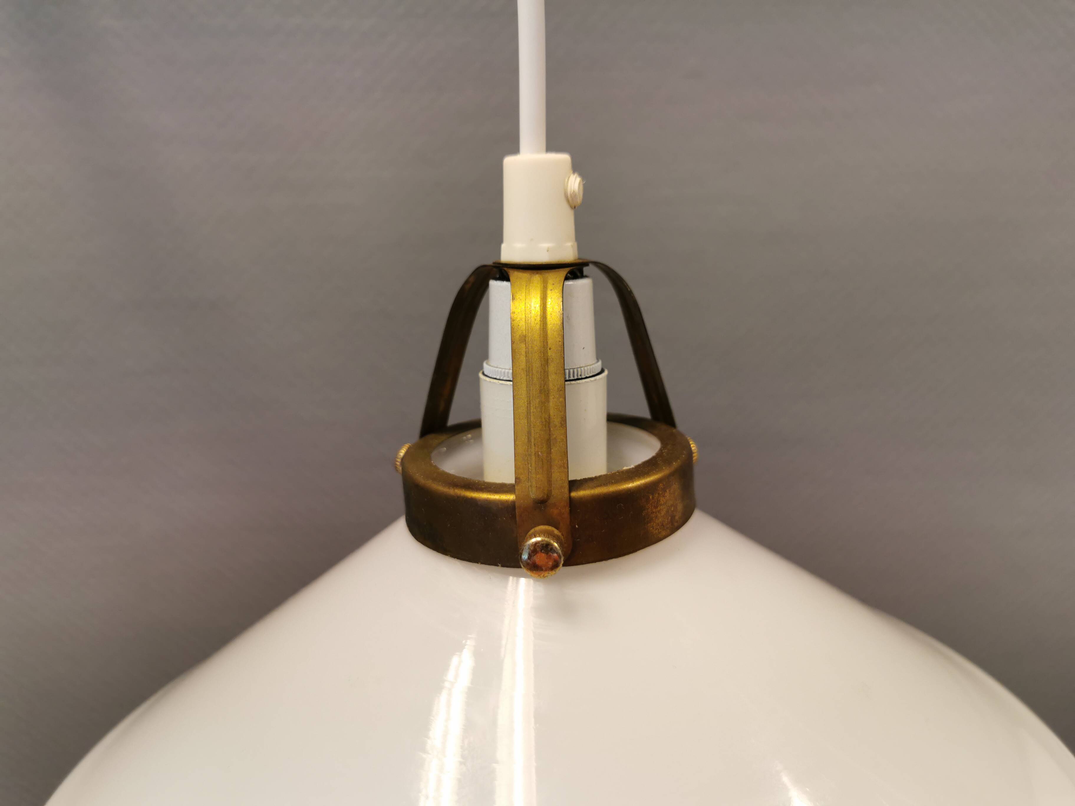 A set of hanging lamps in milky white opal glass with brass top.