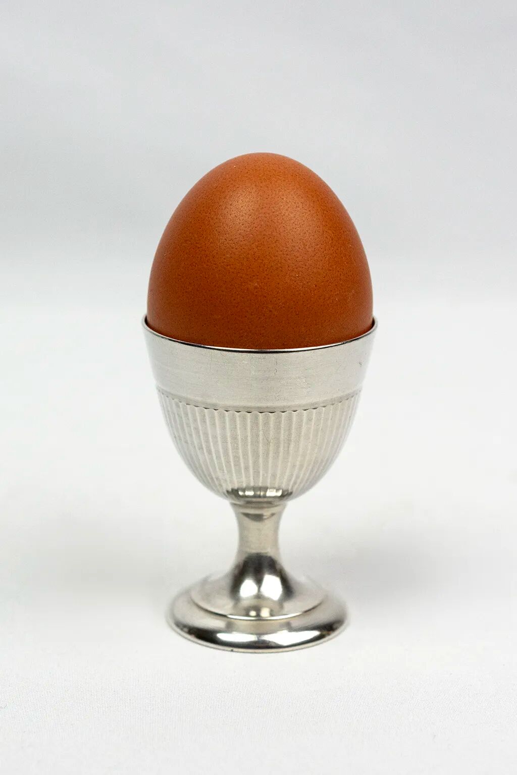 Four silver-plated Christofle egg cups with fluted sides.