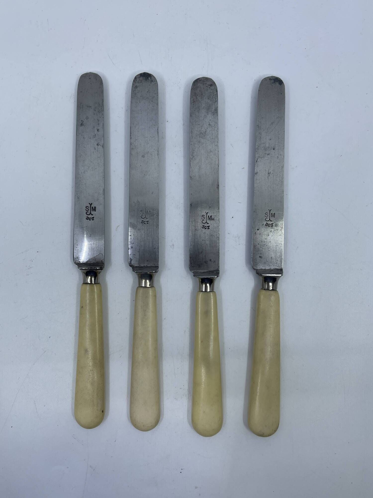Set of 4 dessert knives with rounded blades and smooth ivory resin handles.