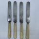 Set of 4 dessert knives with rounded blades and smooth ivory resin handles.