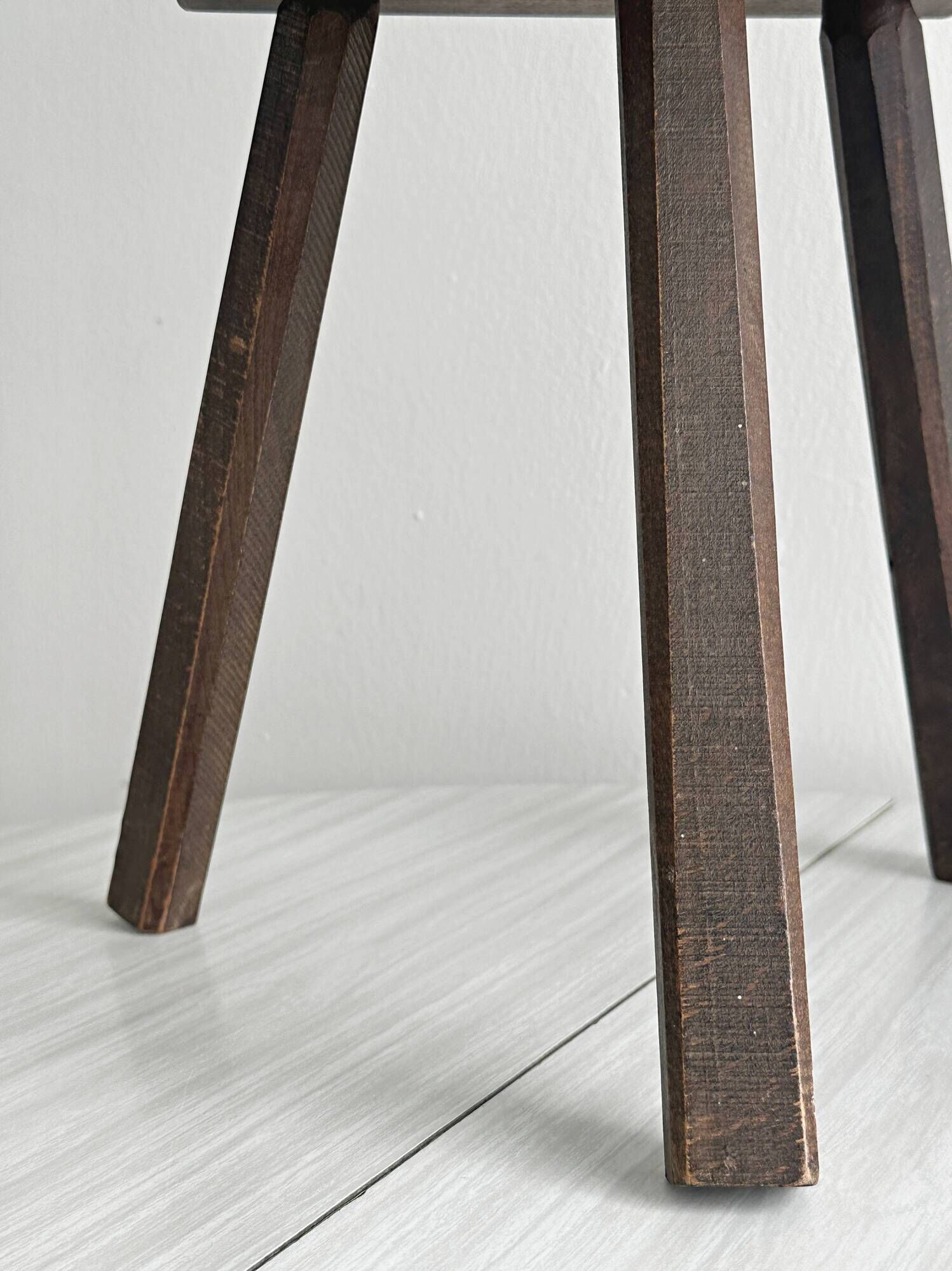 Antique wooden tripod stool with a semi-circular seat.