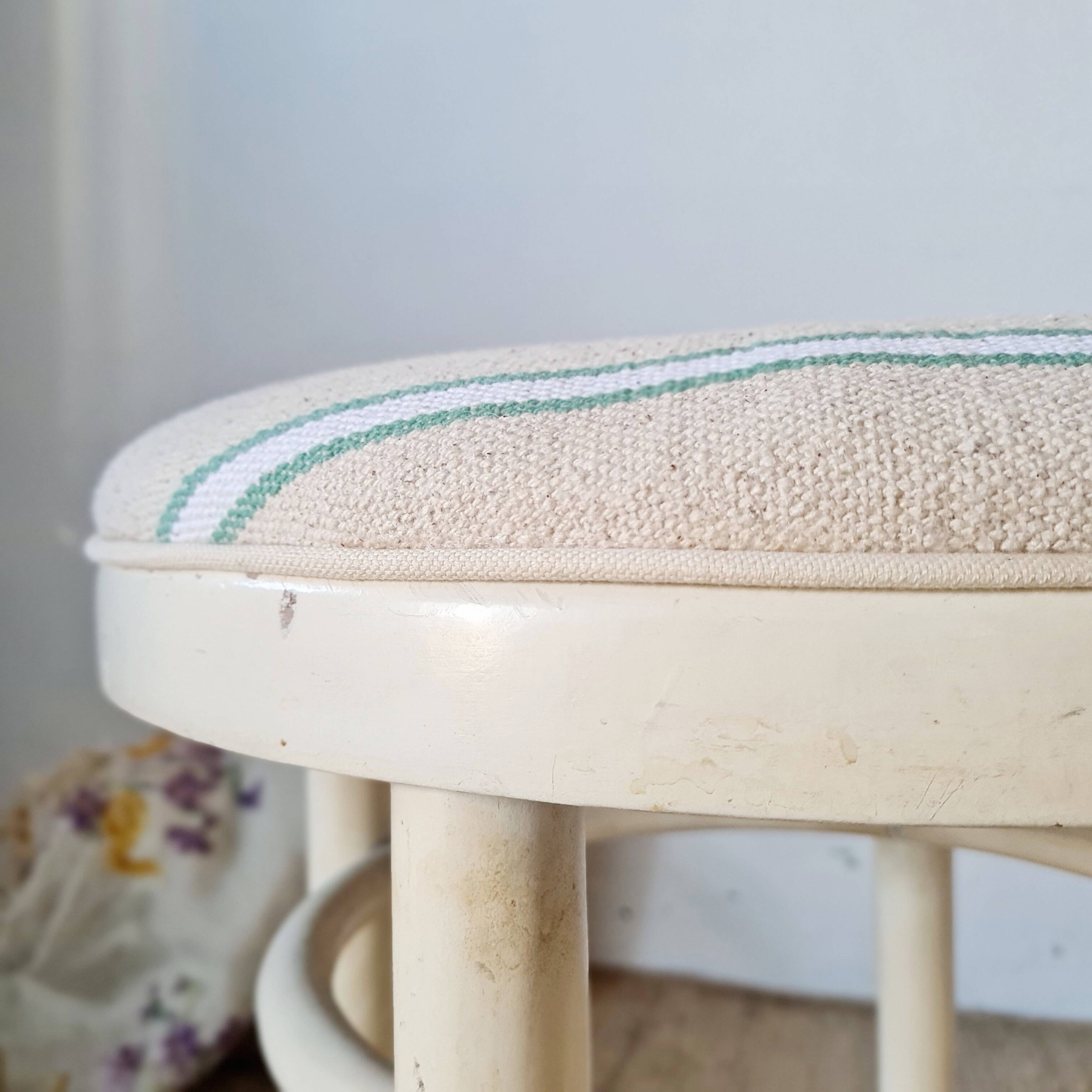 Antique stool with a wooden frame and a cream and green striped fabric seat.