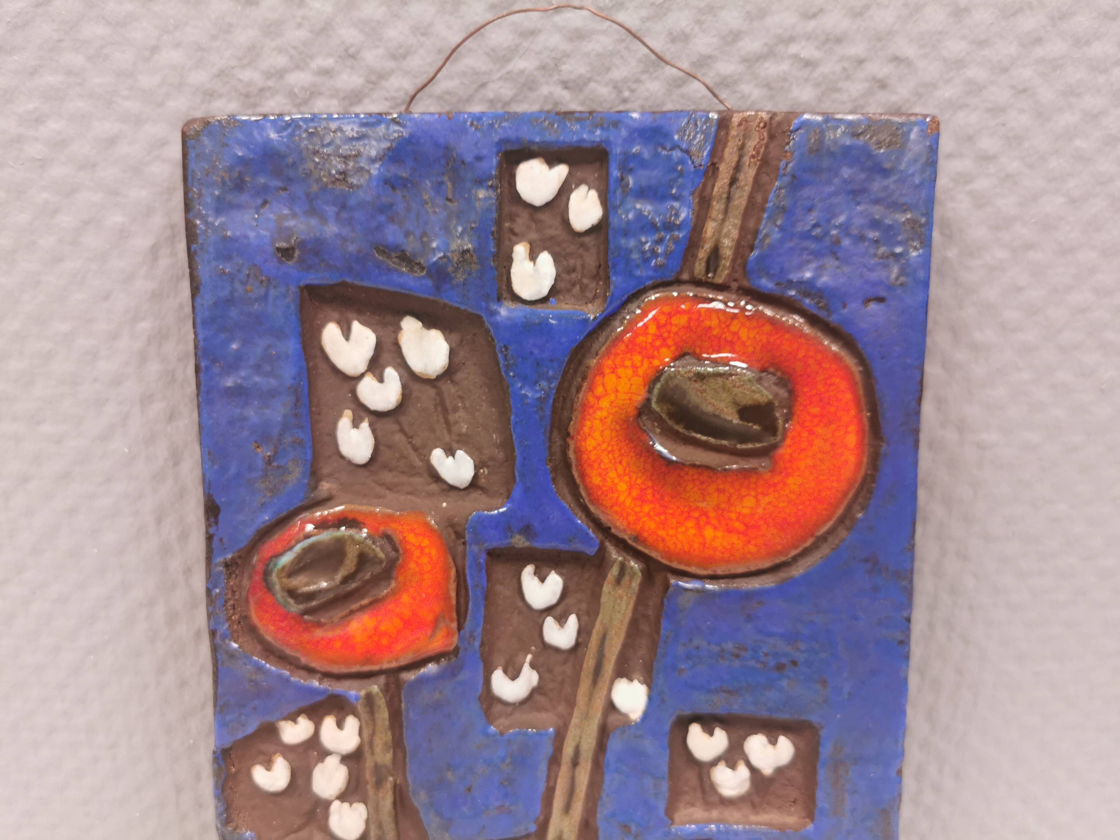 Ceramic relief in attractive blue with a motif of white/red flowers.