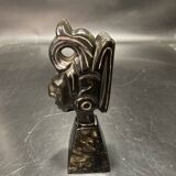 Ceramic sculpture representing a woman's face placed on a black base