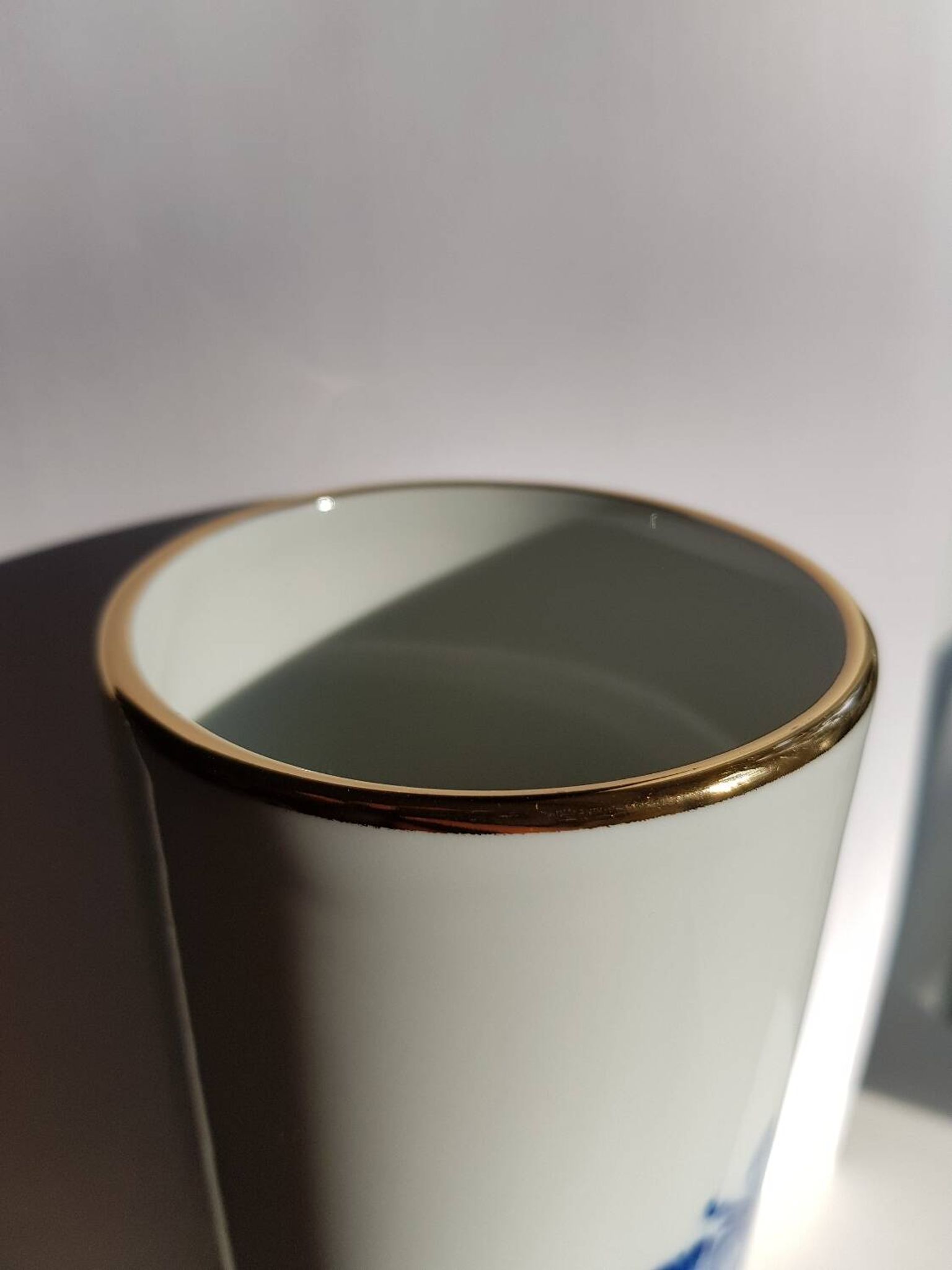 White porcelain vase from Limoges with blue decoration and gold rim.