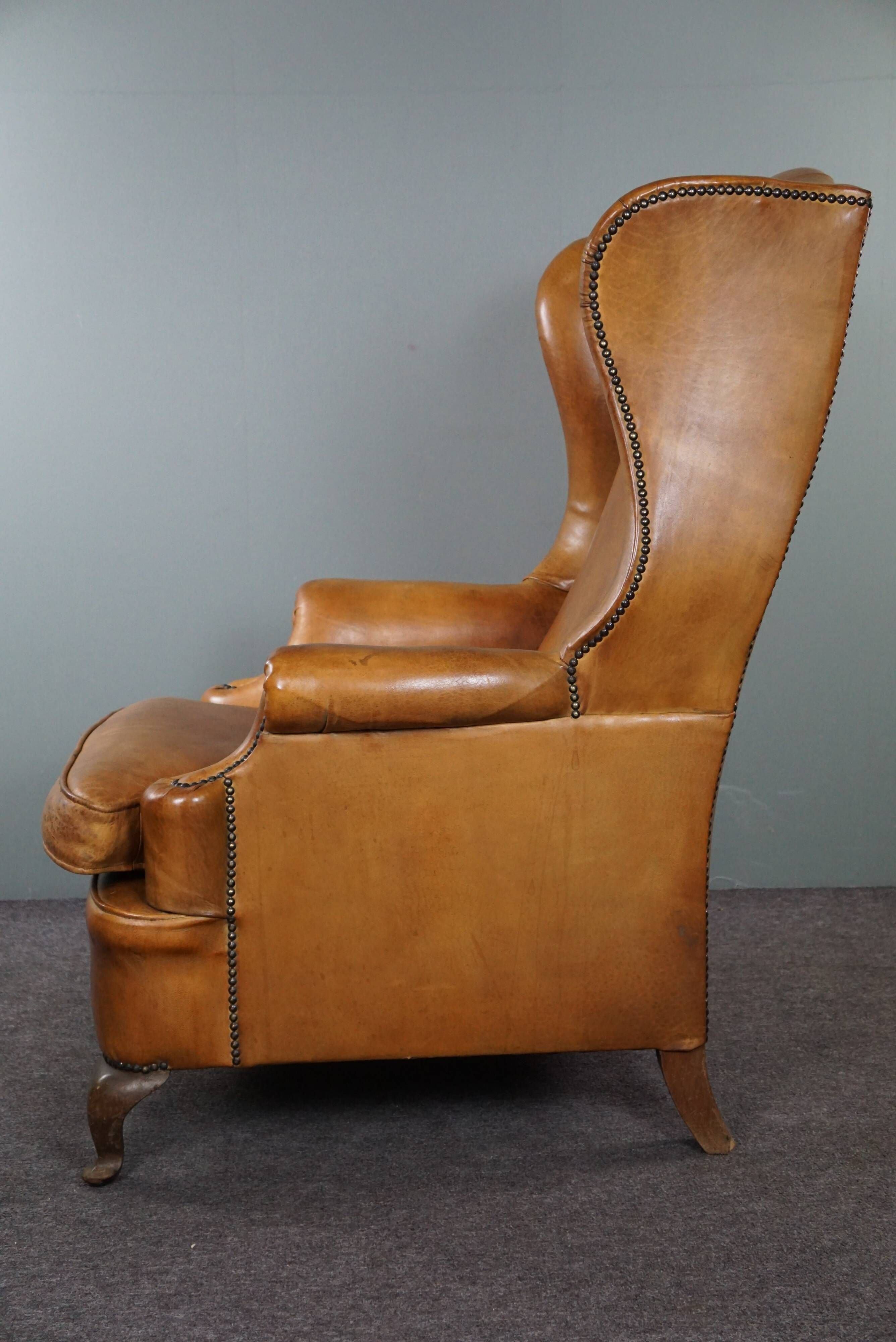 Old wingback armchair made of sheep leather in a correct condition