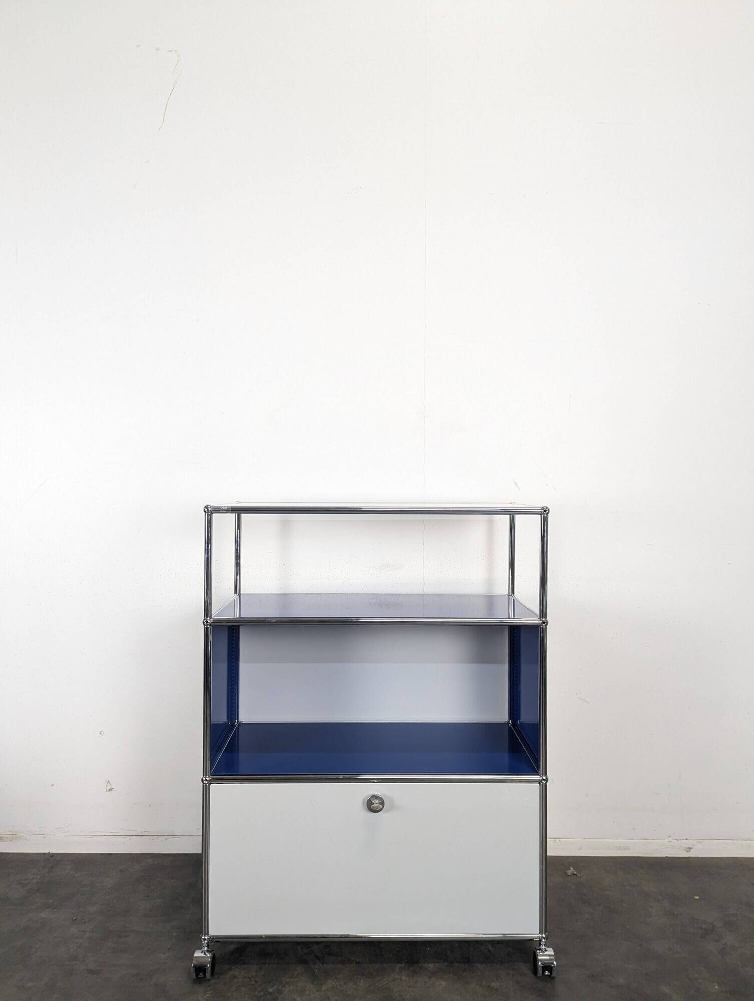 USM Haller furniture in gentian blue and white with a drop-down door on wheels.