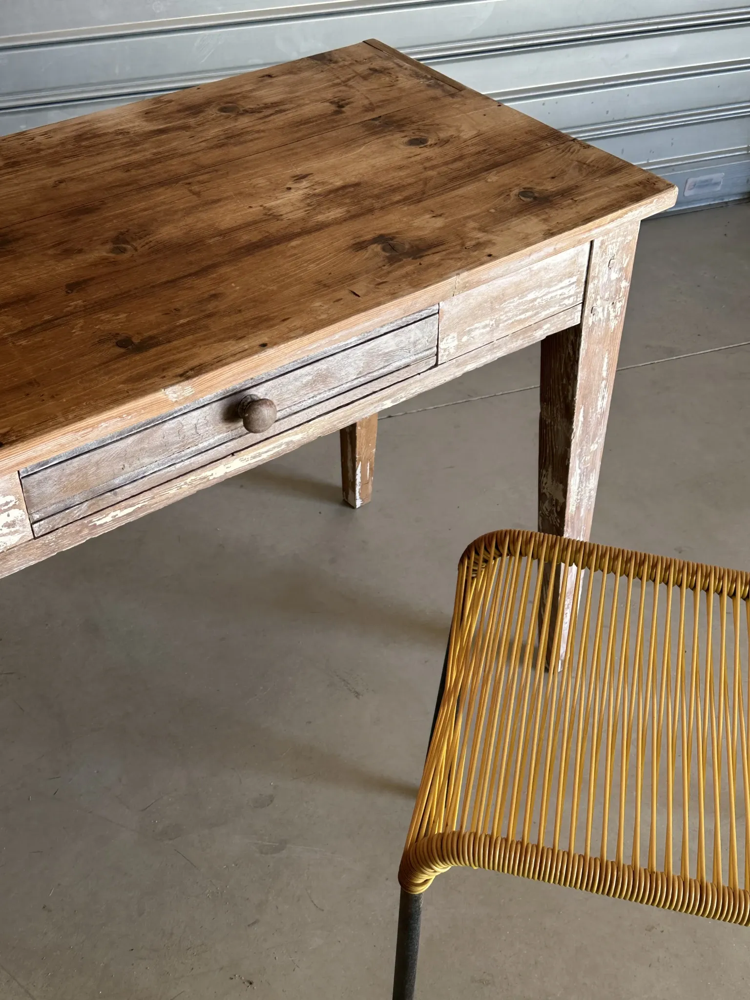Vintage table made of raw wood with a distressed white base.