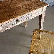Vintage table made of raw wood with a distressed white base.