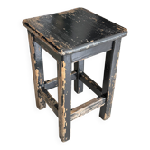 Solid wood stool with a worn black patina.