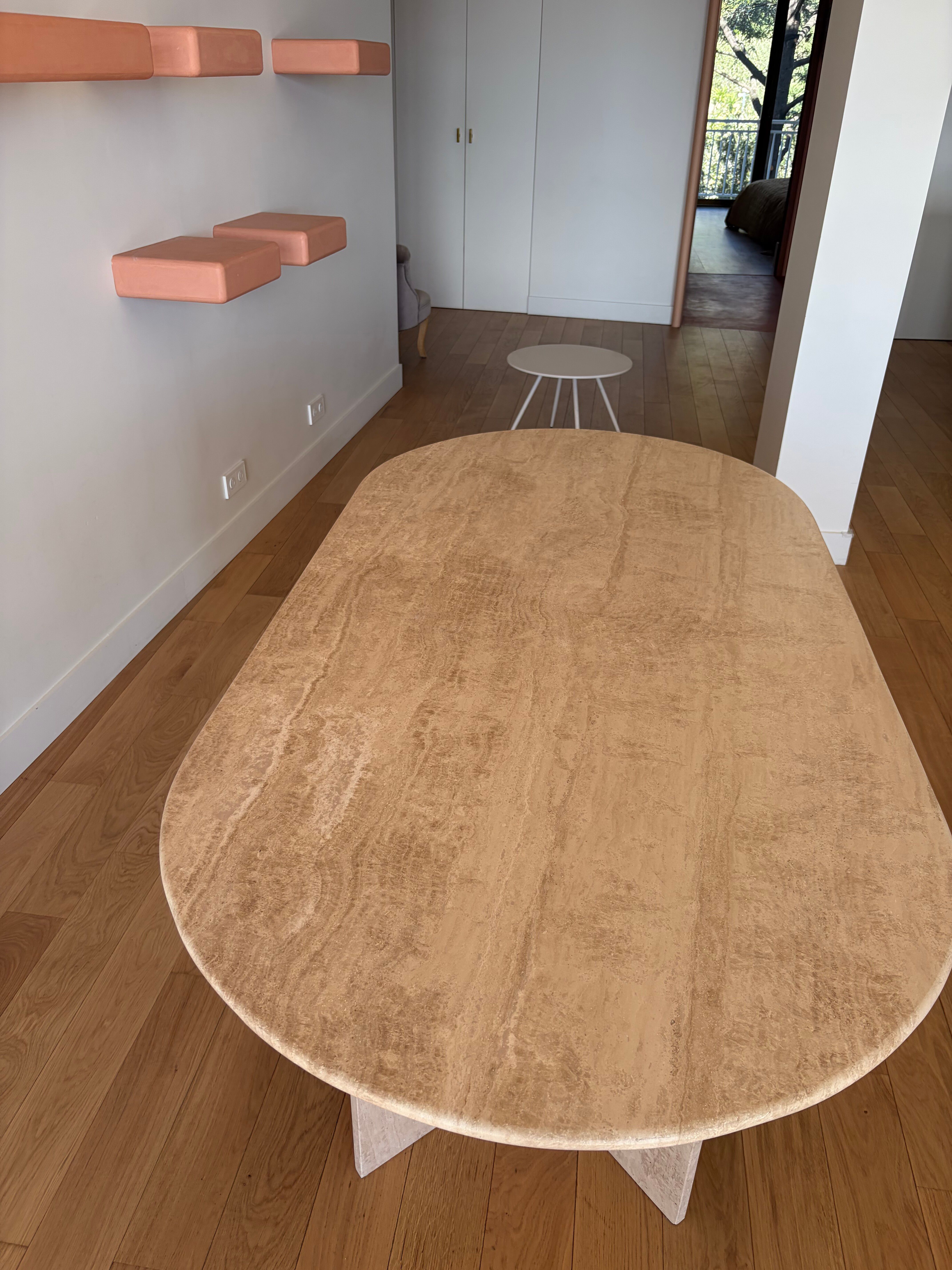 Oblong dining table in beige travertine.
