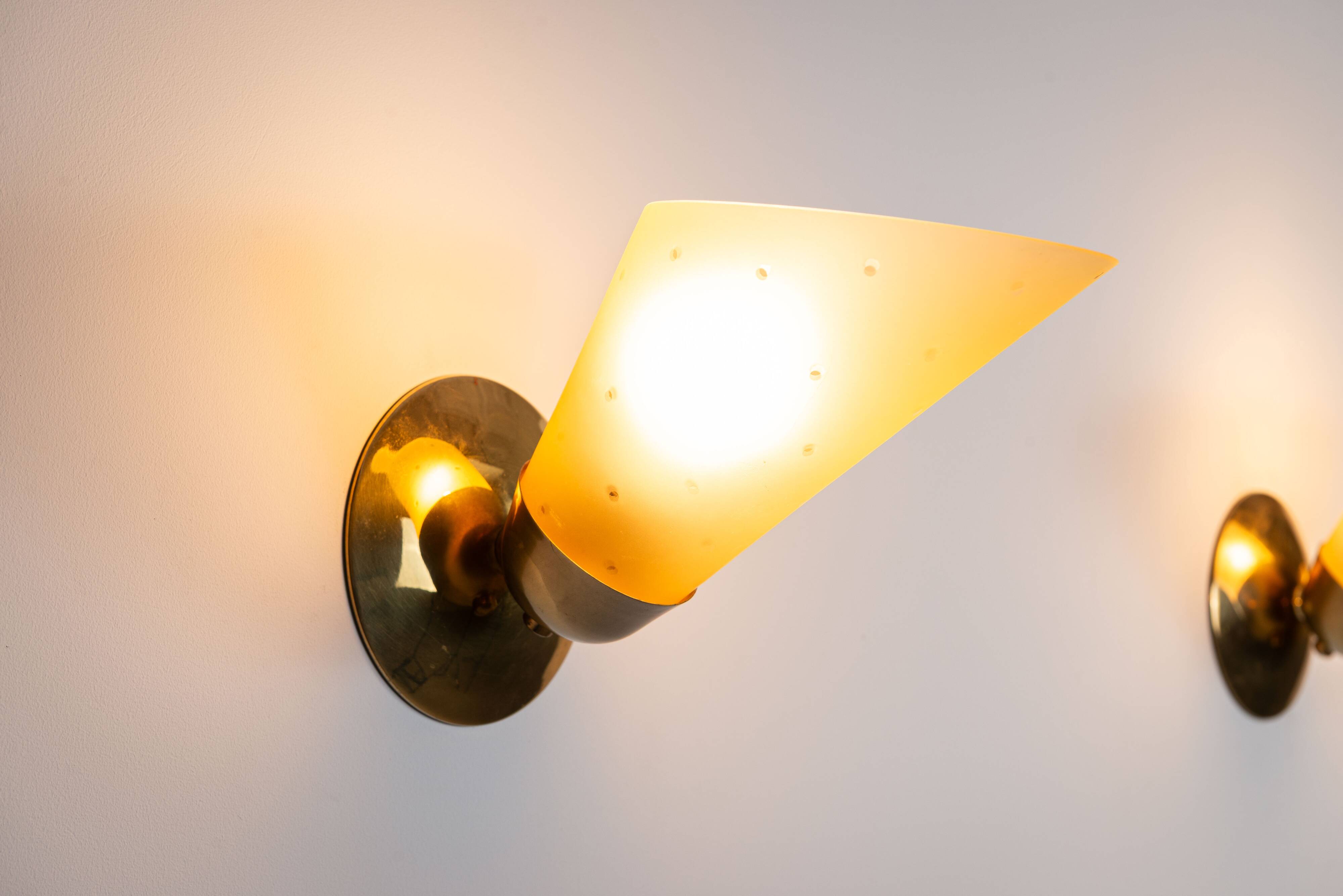 Set of three brass sconces with decorated yellow glass shades