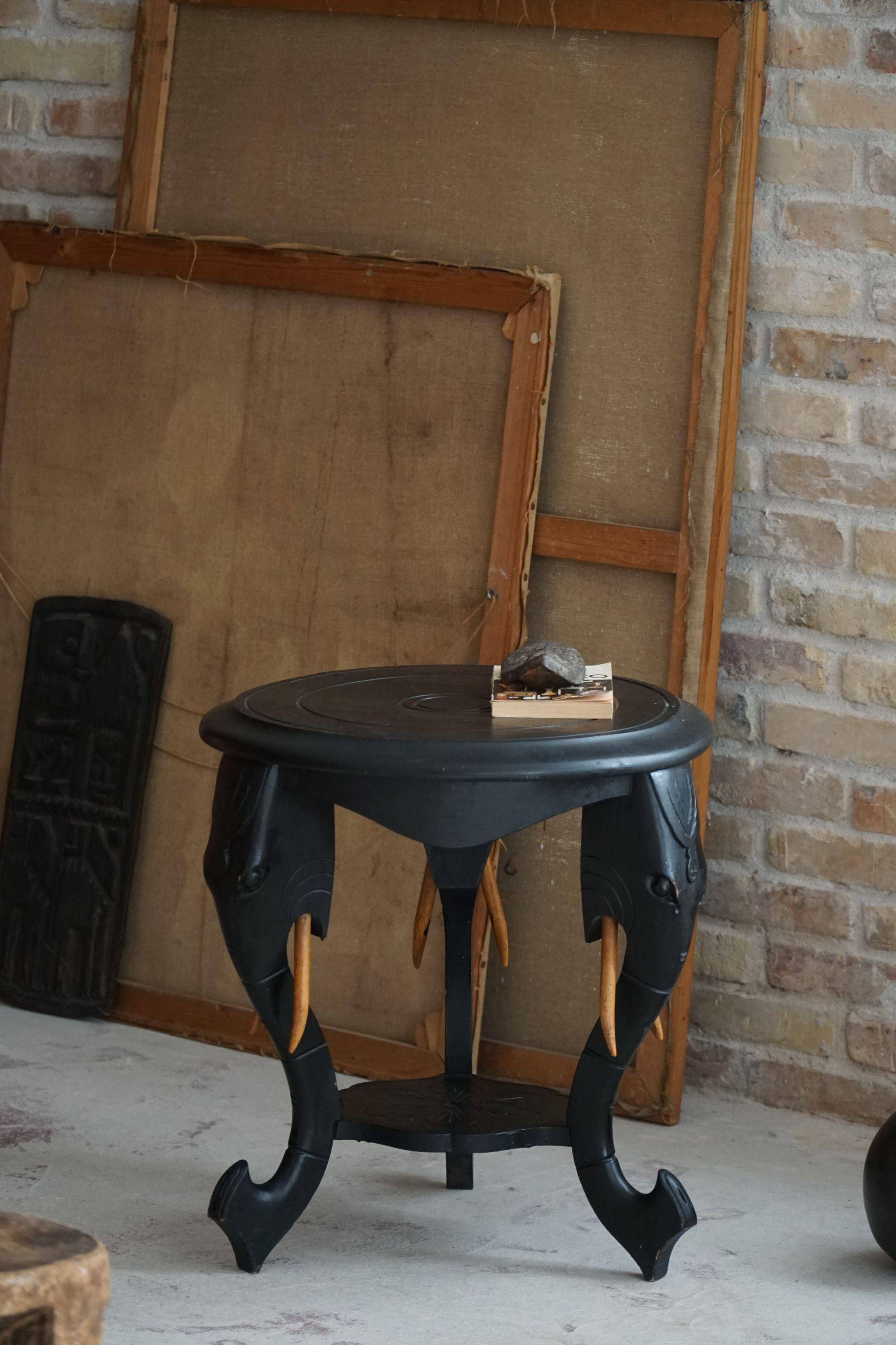 Side table in hardwood ebony with three elephant head-shaped legs, Eastern India, 1920s.