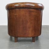 Subtle, neat sheepskin leather club armchair with a fixed seat cushion in a deep, dark cognac color