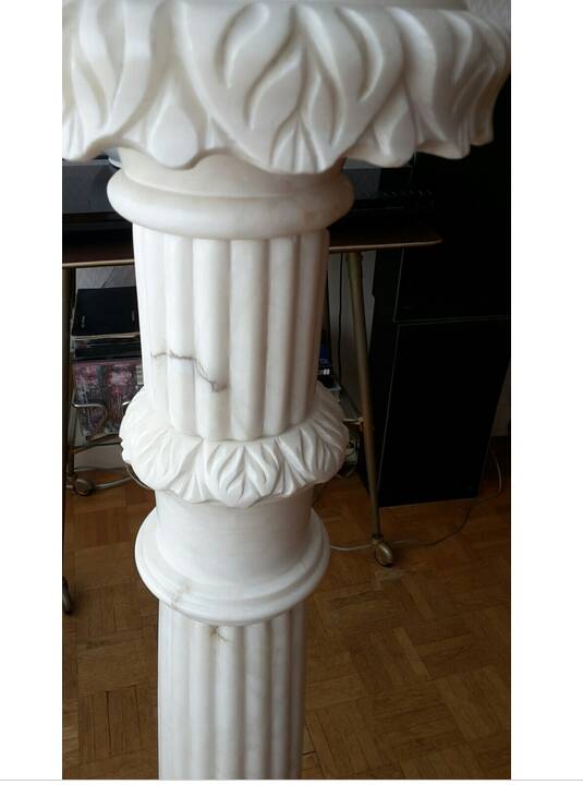 Fluted white marble stand column with floral motifs.