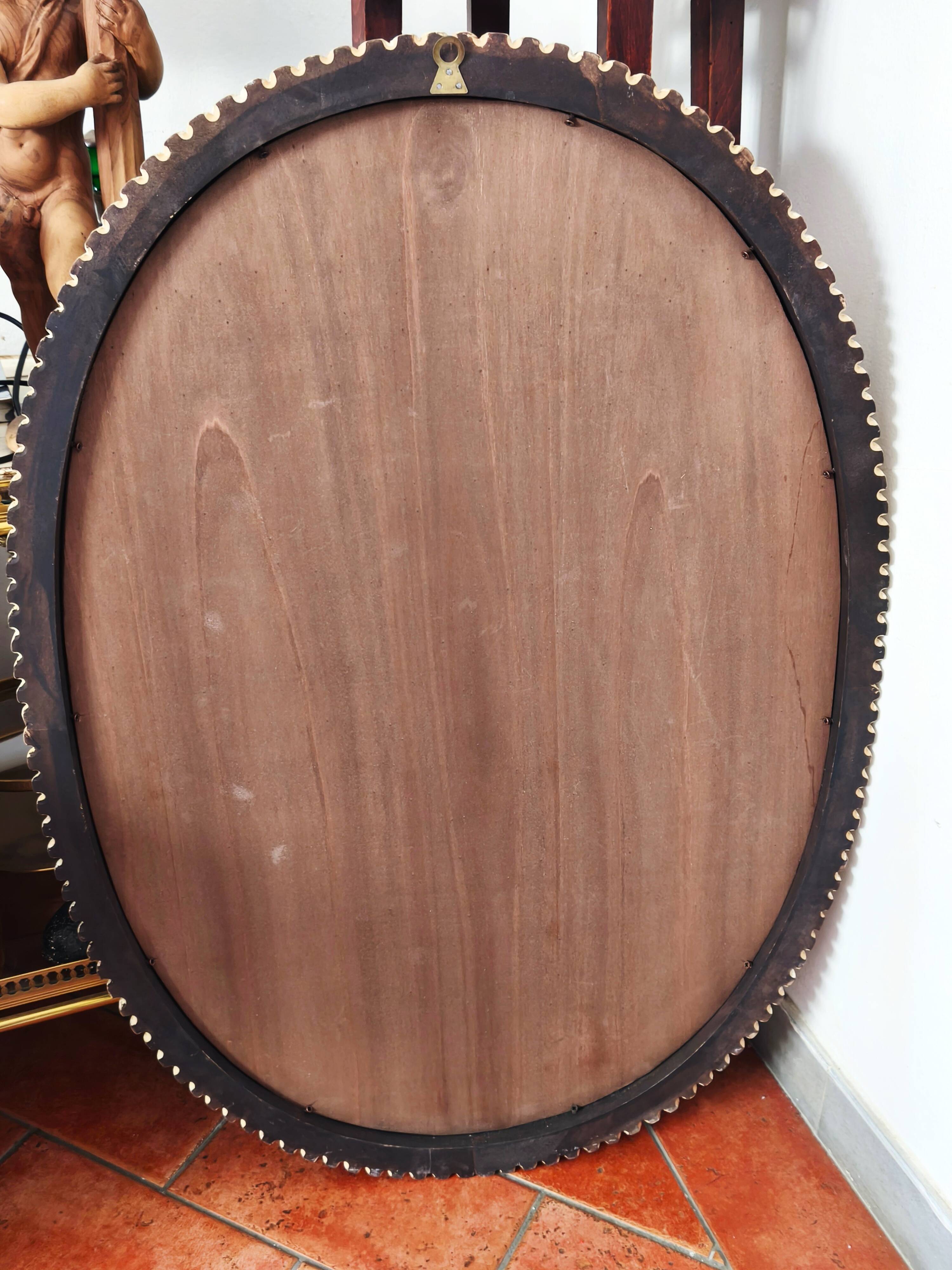Large oval Florentine mirror in carved wood and gilded with gold leaf.