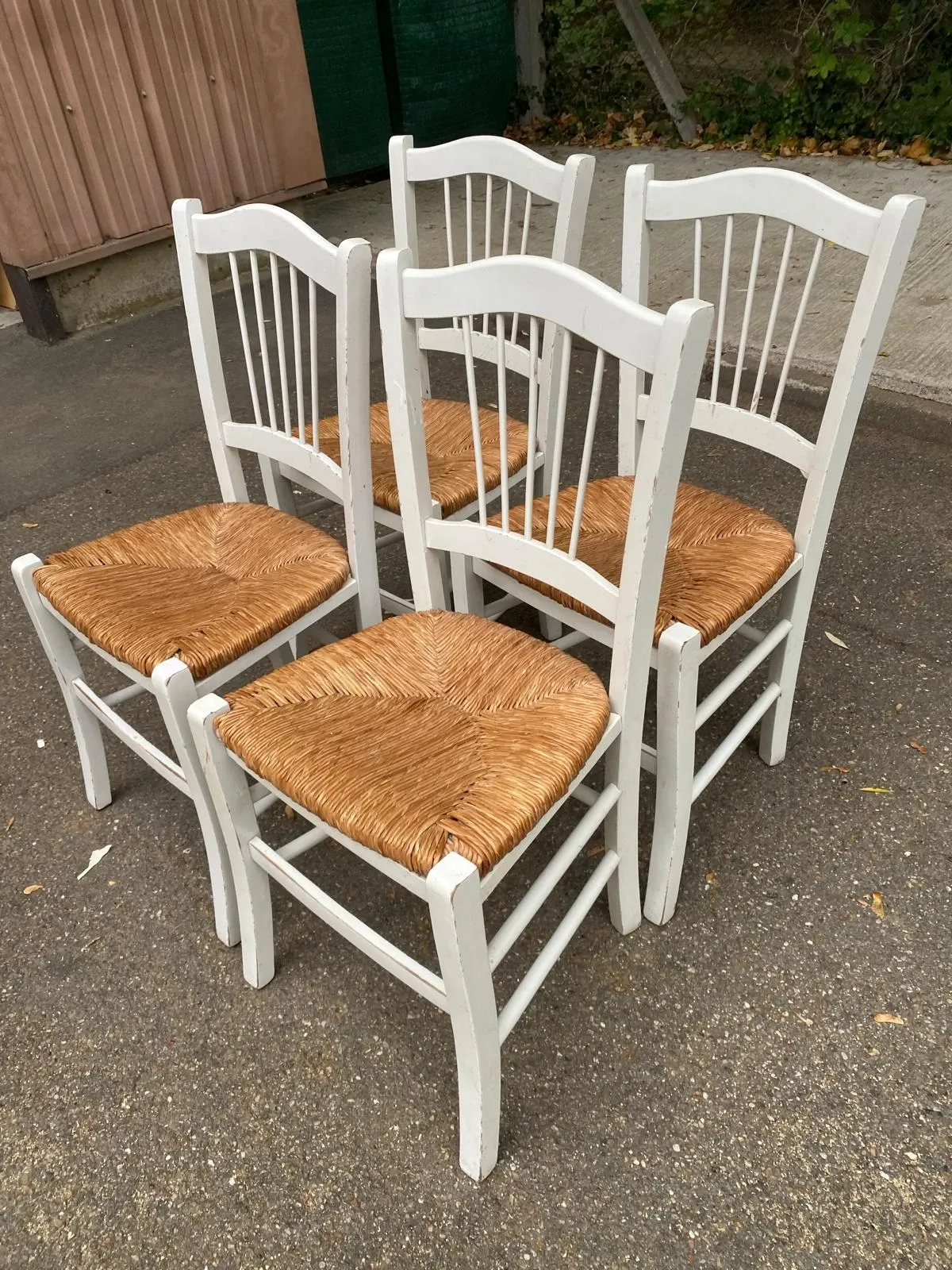 Set of 4 rustic white wooden chairs with straw seats.