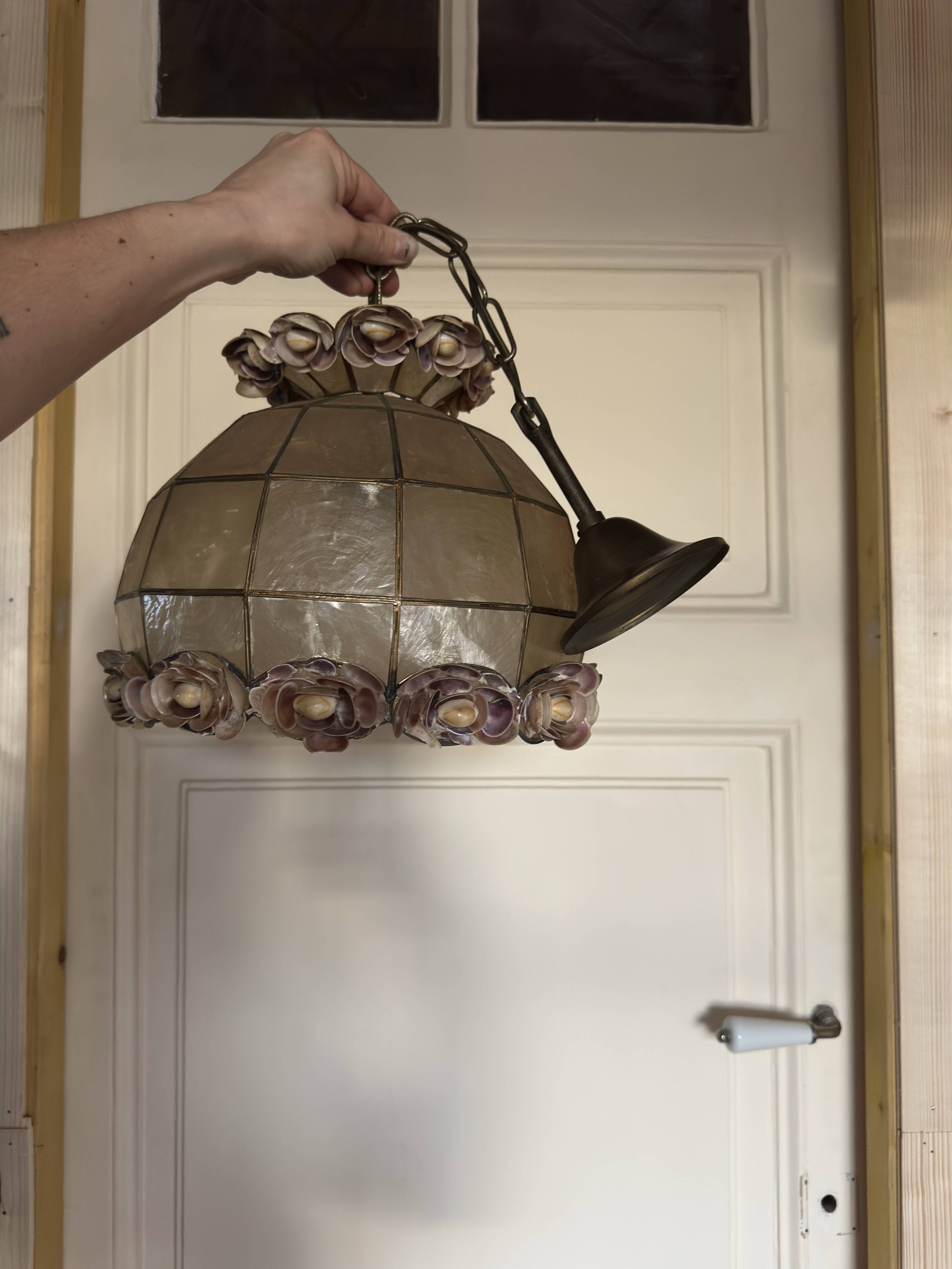 Vintage pendant light with a pearlescent shade and floral decoration.