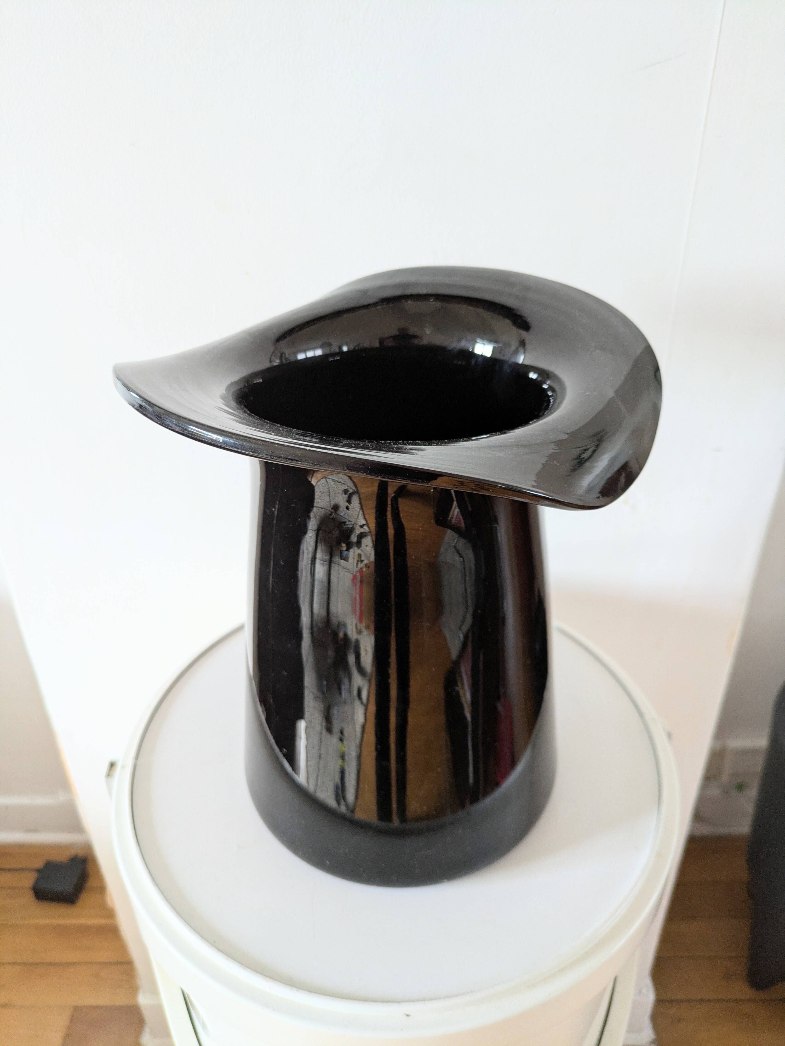 Large black glass vase topped with a 70s hat