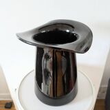 Large black glass vase topped with a 70s hat