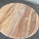 Round extendable dining table stripped in solid raw walnut with a central leg.