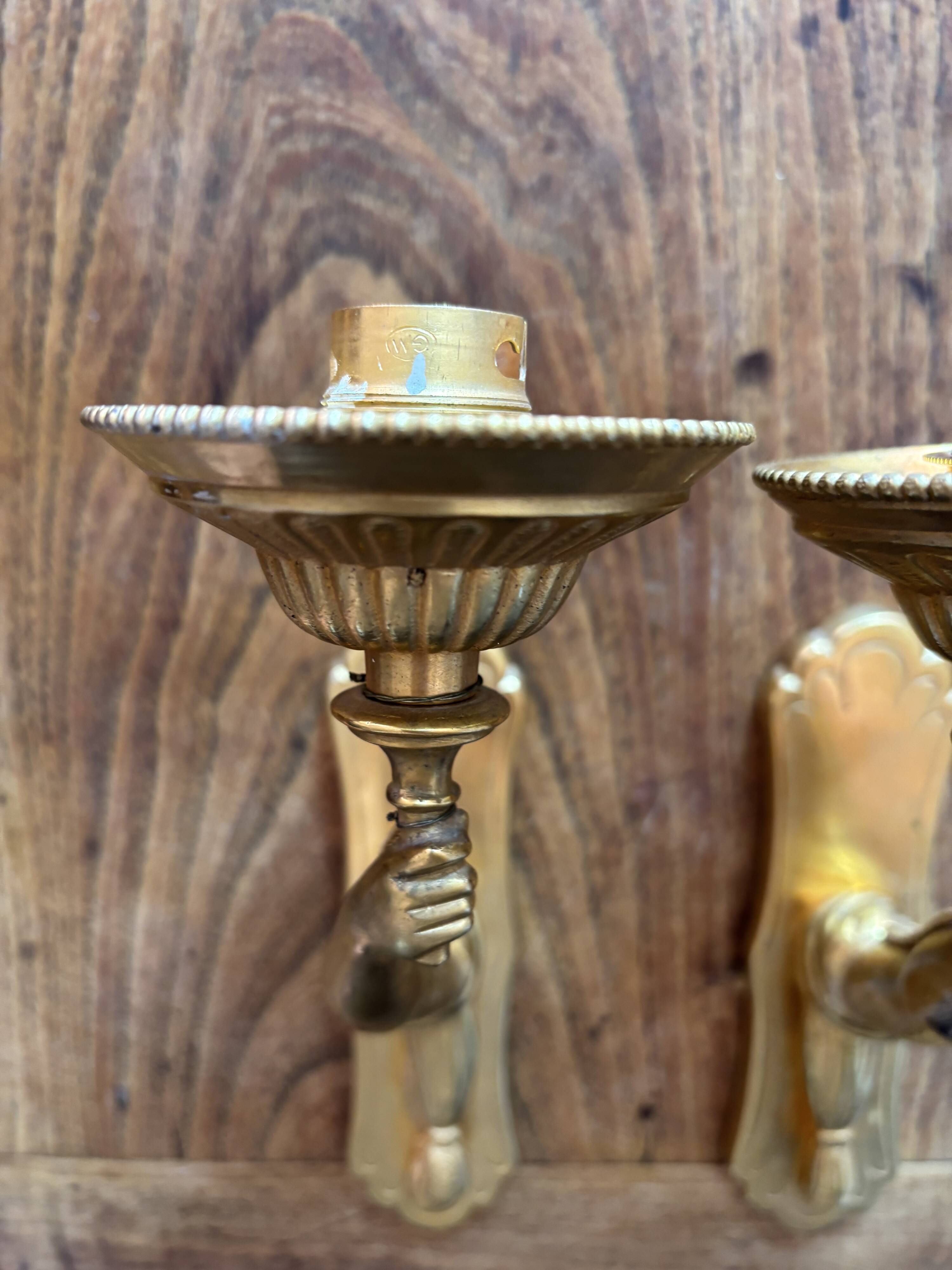 Pair of bronze wall sconces with outstretched arms and hands