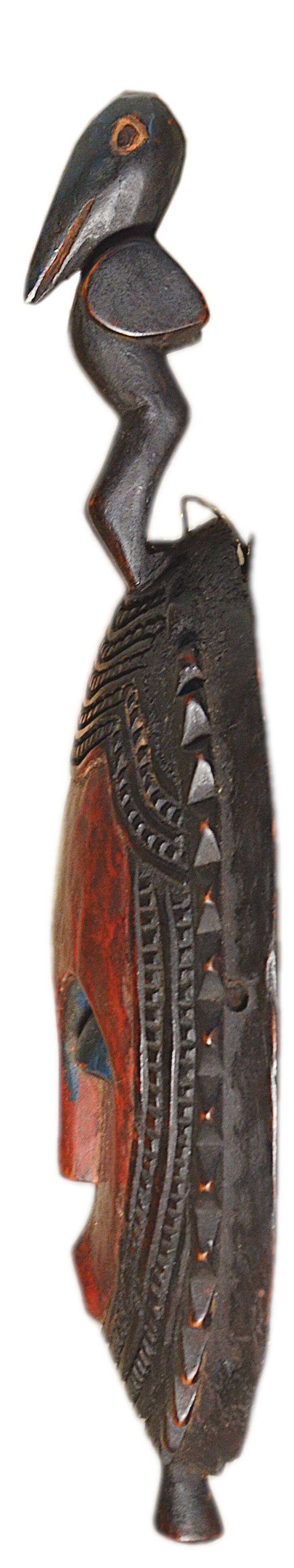 African wooden mask, face topped with a bird.