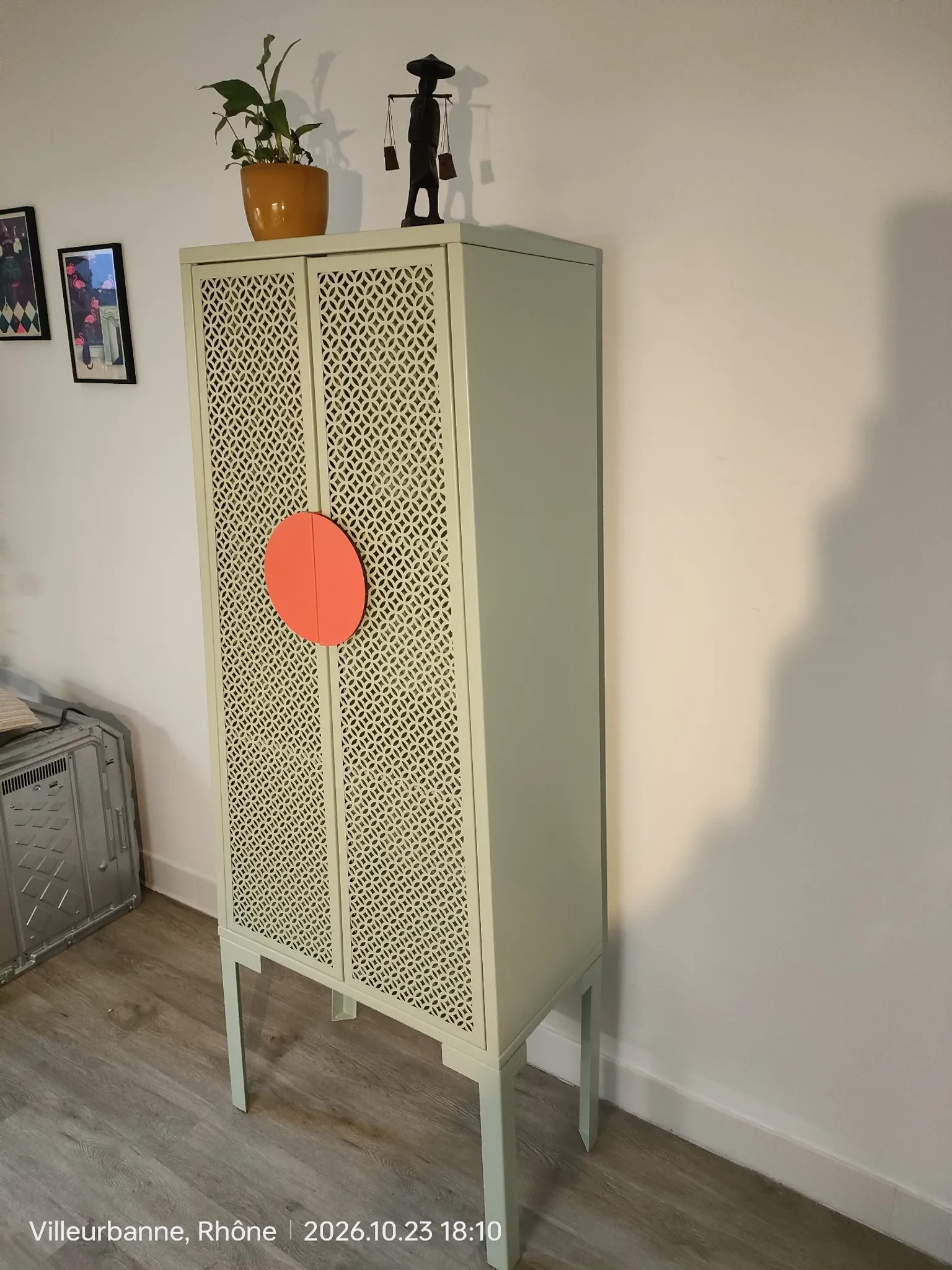 Vintage sage green metal wardrobe with louvered doors and coral handles.