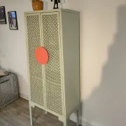 Vintage sage green metal wardrobe with louvered doors and coral handles.