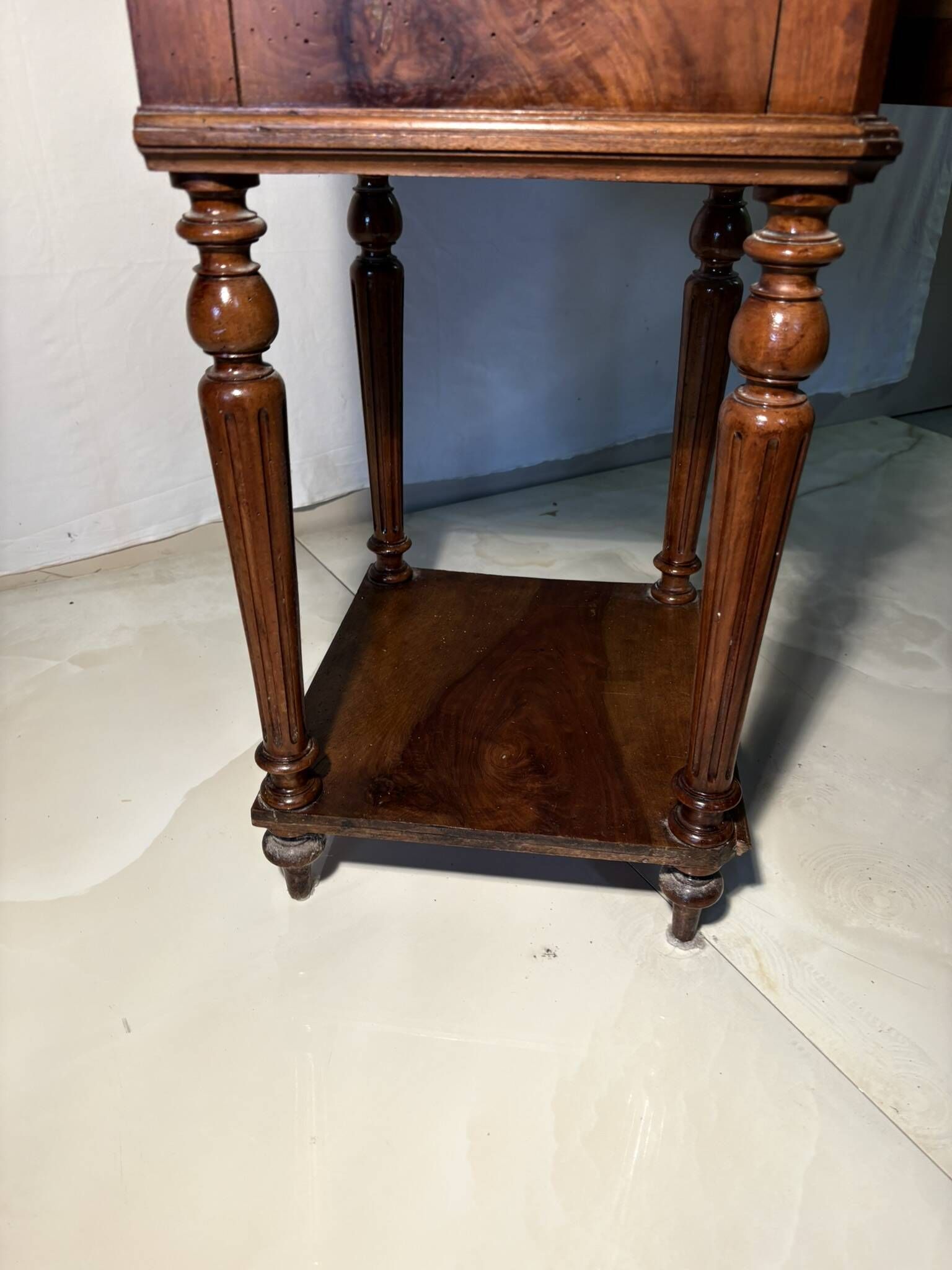 Antique wooden bedside table with turned legs.