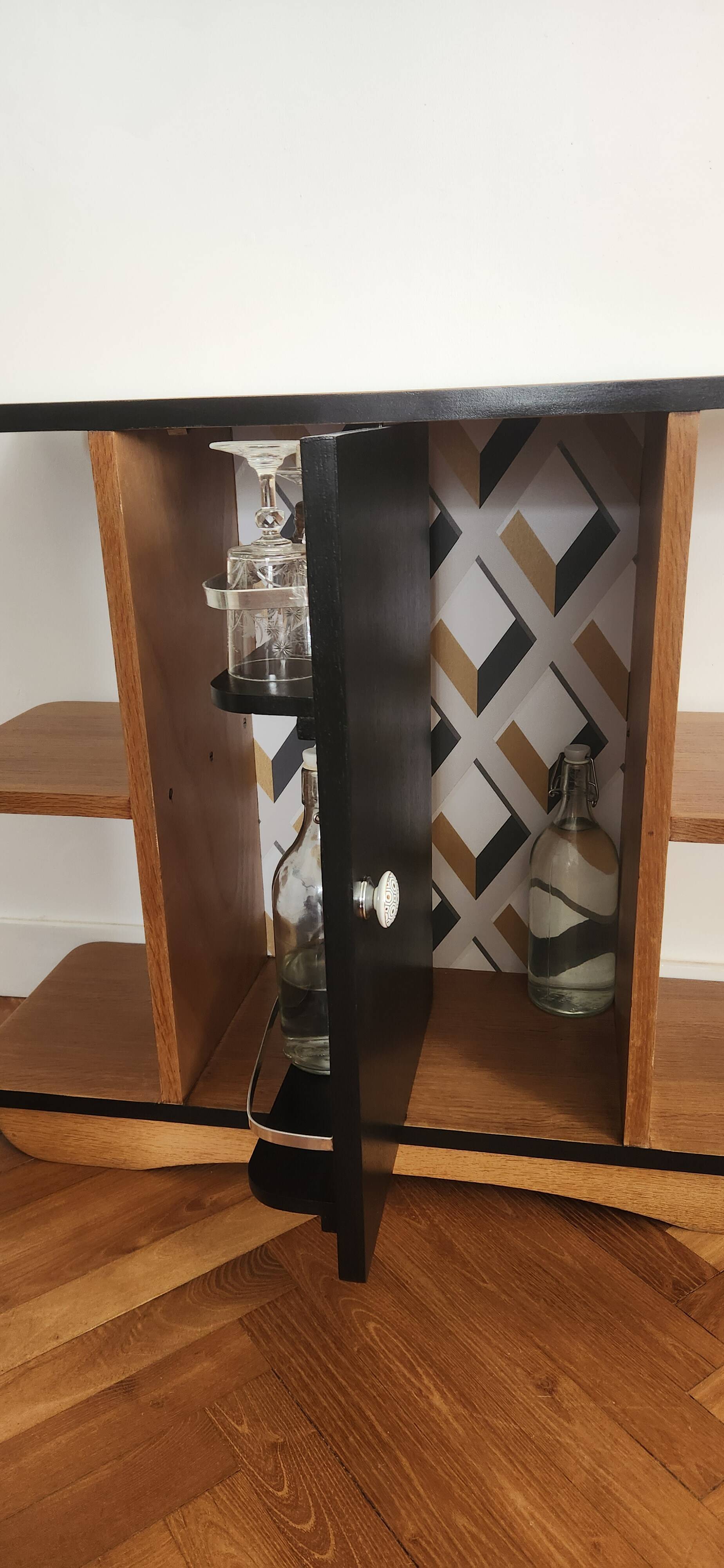 Compact bar cabinet with a pivoting door in black wood.