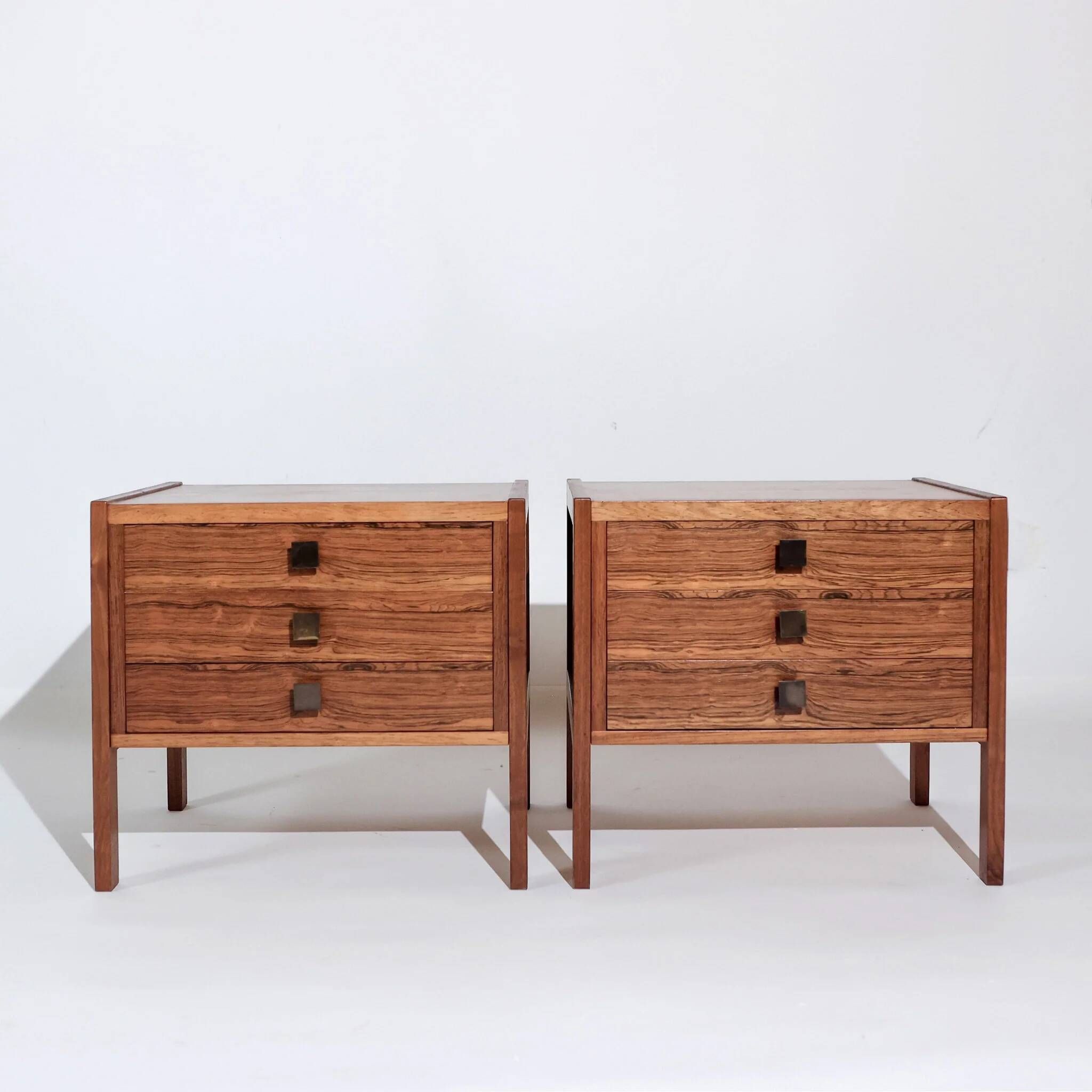 Pair of vintage Scandinavian bedside tables, three drawers, honey-toned wood.